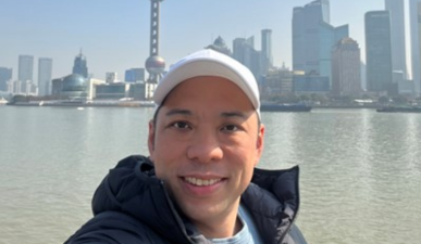 Man wearing white cap smiling with city backdrop behind