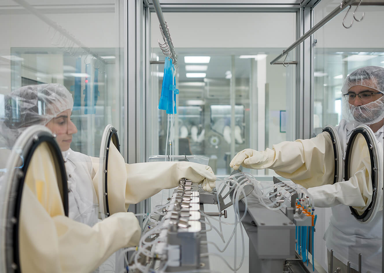 2 employees in full scrubs, working inside a lab