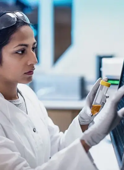 female person in lab coat handling a test tube