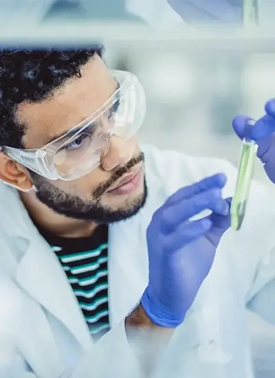 male person in lab coat inspecting a test tube