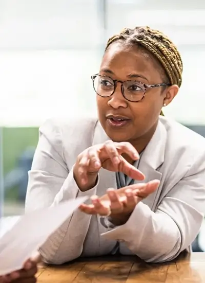 black female person in business attire, speaking and making hand gestures