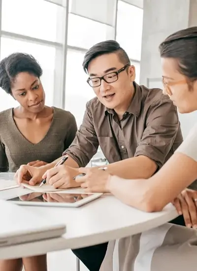 coworkers gathered around a table and conversing over a tablet device