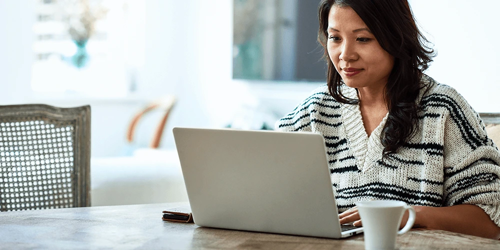 employee in comfortable attire, seated behind a laptop and cup of coffee