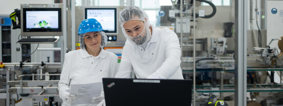 2 female employees in business attire, walking through a large office space