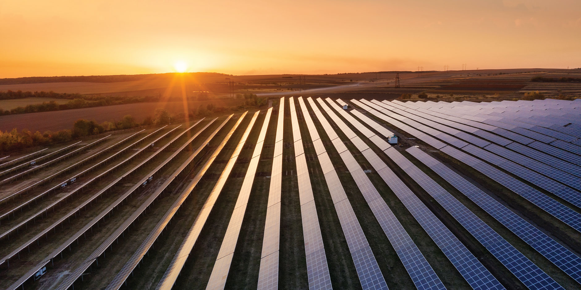 "Rows of solar panels in a field with the sunset in the background"