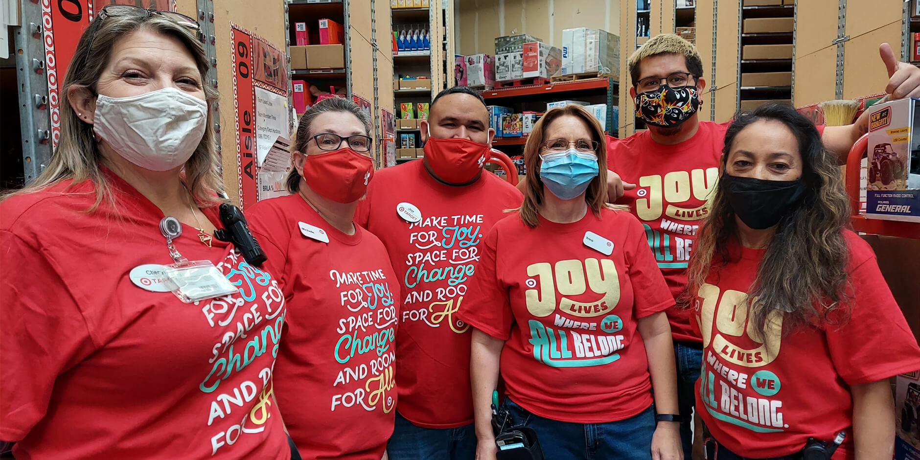 Six Target team members in red shirts with inclusive sayings and masks smile for the camera.