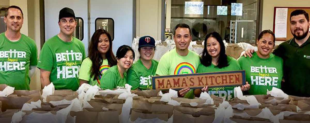 A group of 9 colleagues volunteering at a food pantry together, looking happy