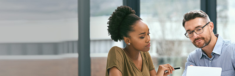 A woman and a man working together, in an open office