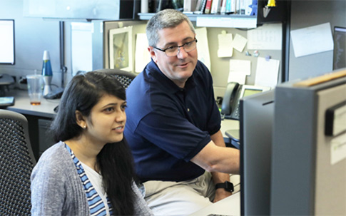 Two finance employees conversing about what they see on a computer monitor in a friendly fashion