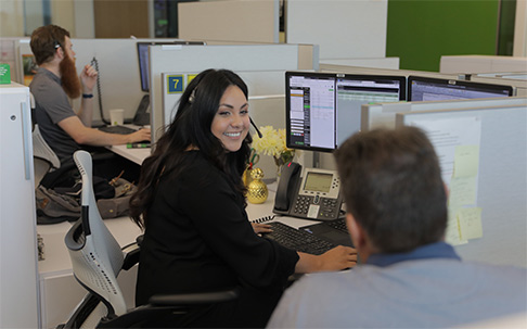 Two administrative colleagues conversing in an open office 