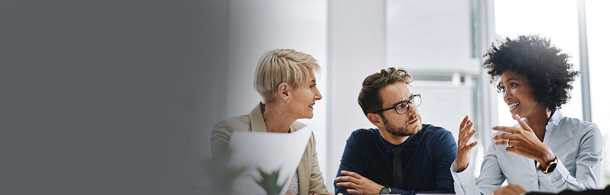 A small meeting over coffee, with a woman employee explaining a topic while the two other employees watch