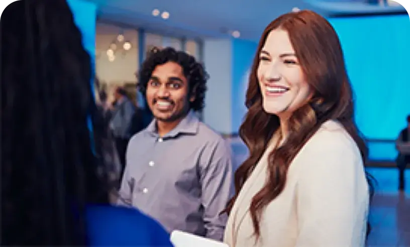 Woman in business suit is smiling while talking to two others