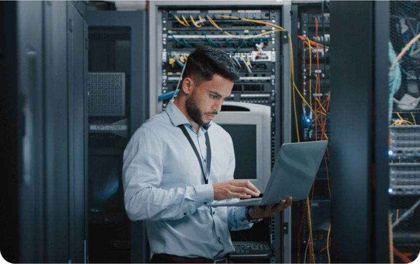 Man in Server room, looking at laptop