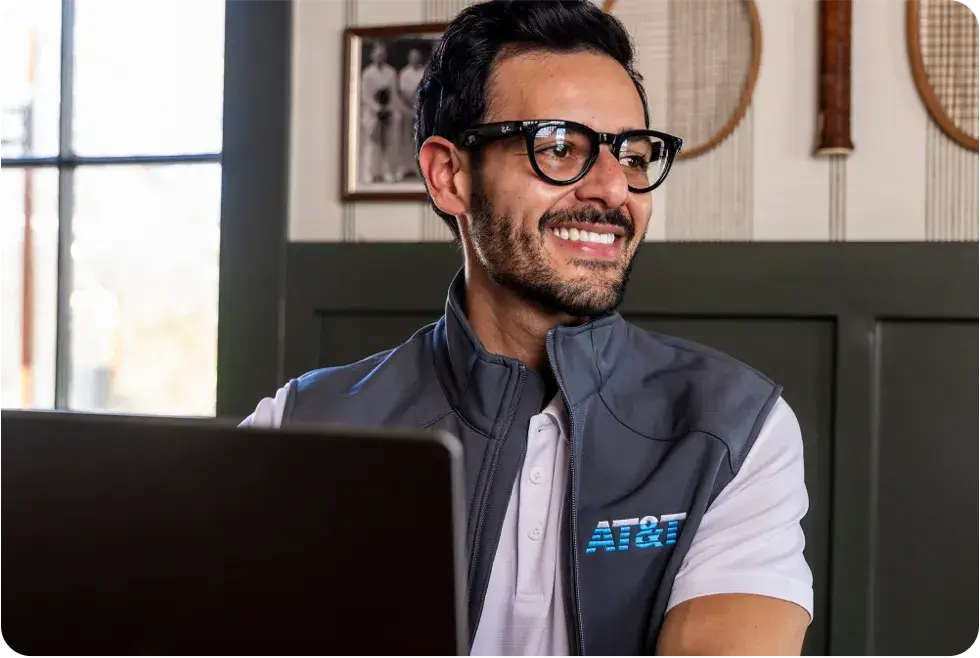 Male AT&T employee wearing an AT&T vest jacket while sitting at a computer