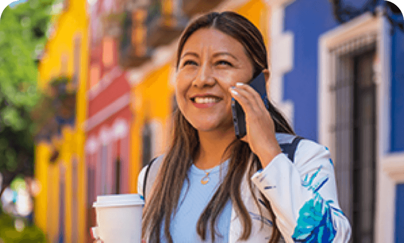 Hispanic female on cell phone and holding a to go cup of coffee