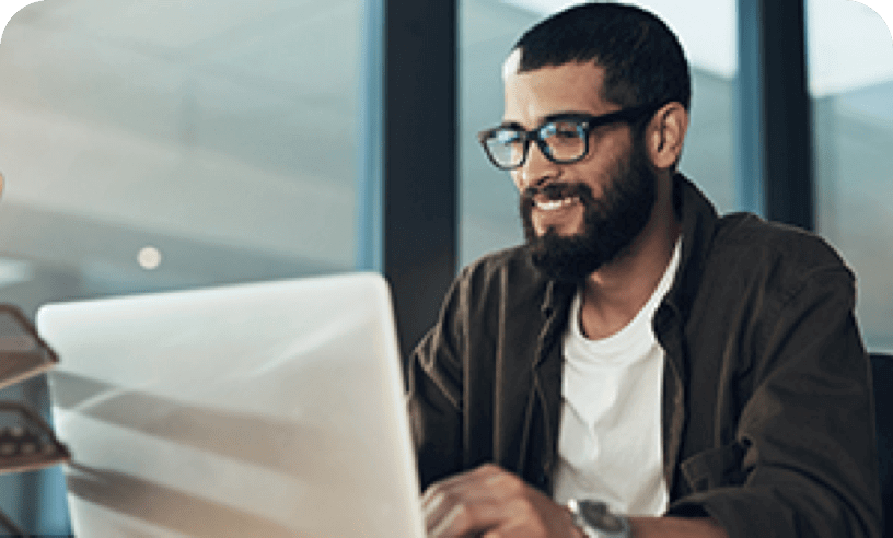 Hispanic male sitting at desktop while working on laptop
