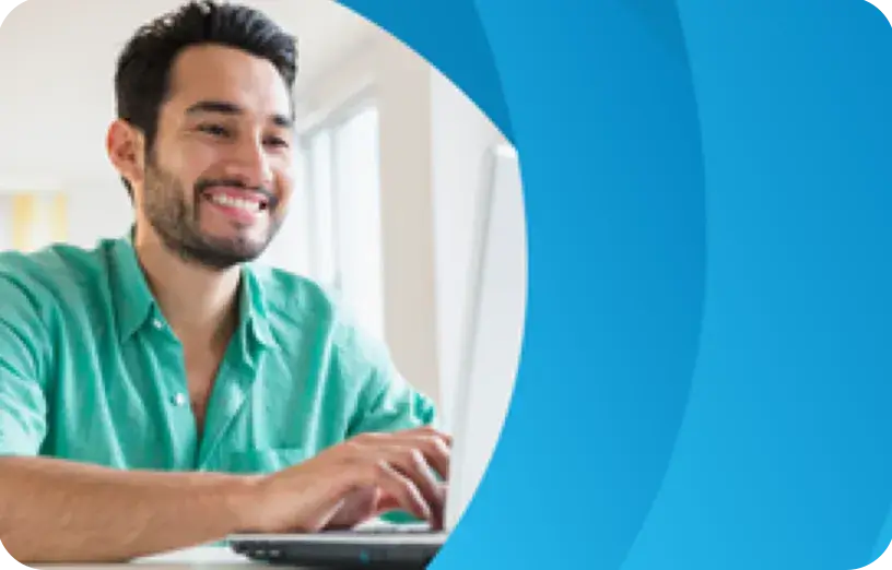 Hispanic male sitting at desk while working on a laptop