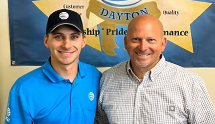 Two employees standing together in front of a company banner.