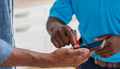 Close-up of two people interacting with a smartphone, with one person pointing at the screen.