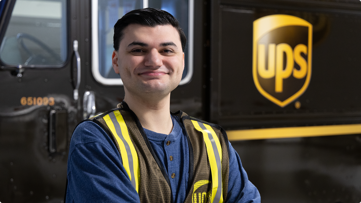 UPSer smiling proudly at camera in front of UPS Brown truck