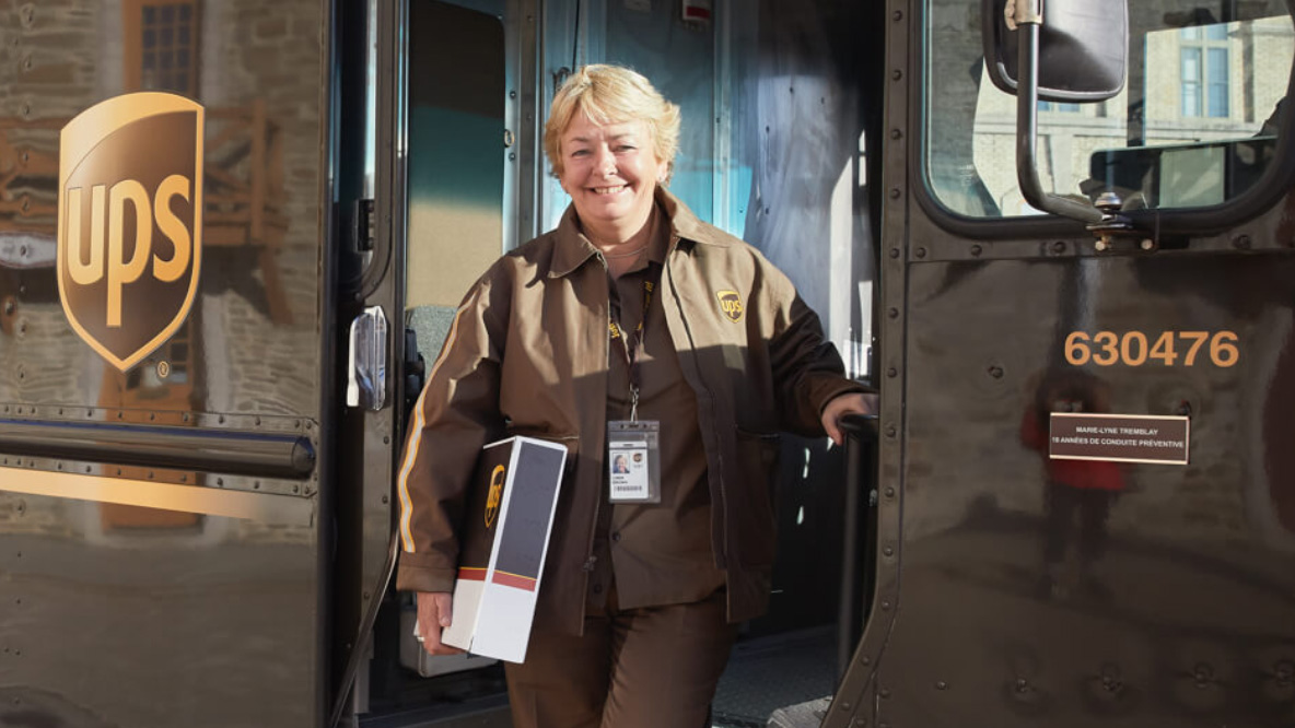 Female employee holding a package and stepping out of a UPS delivery truck