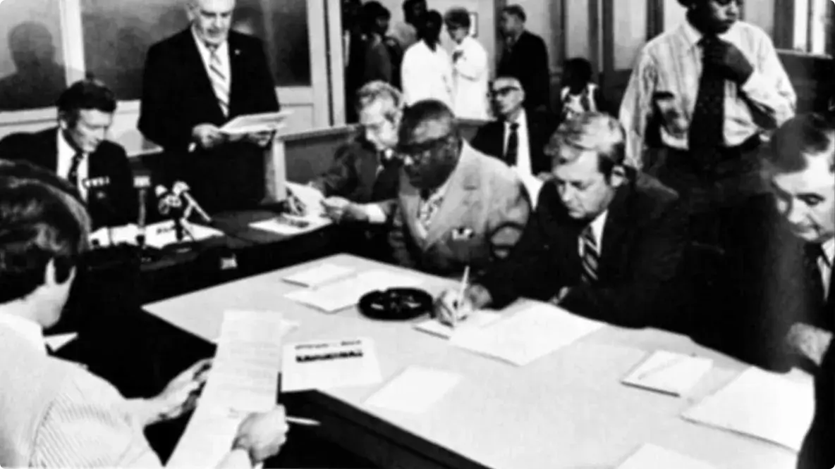 Old picture from 1971 of well-dressed men sitting around a table.