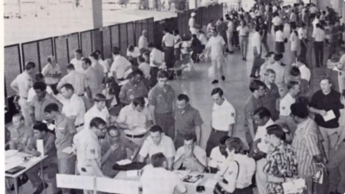 Old picture from 1973 of large room with people meeting at various tables.