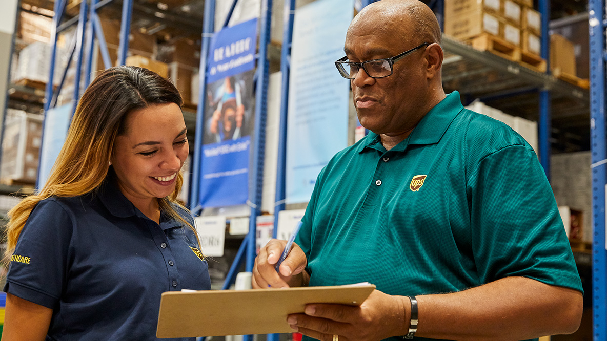 Man showing a women a clipboard in a UPS facility