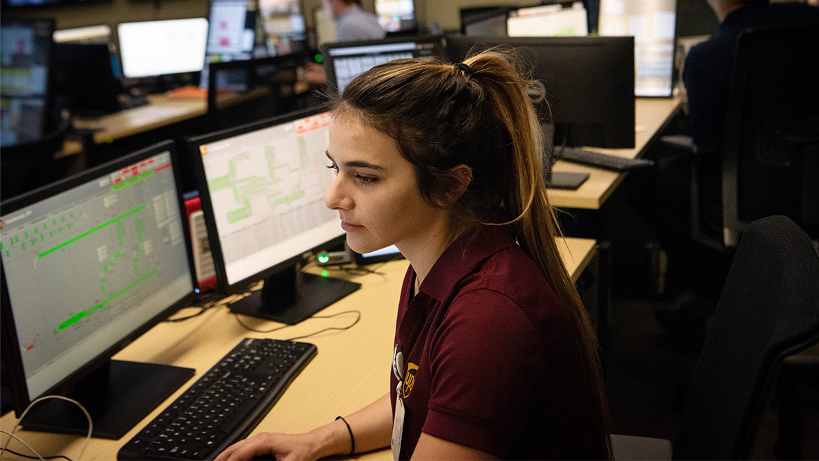 Female intern sitting at a desk, looking at  computer screens