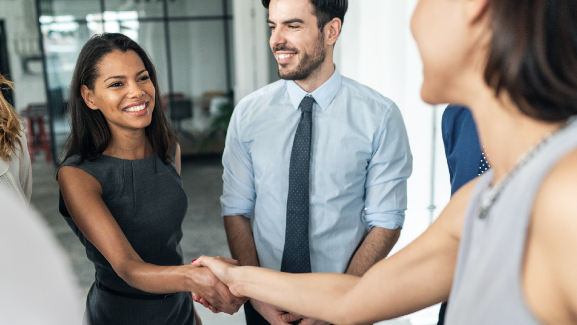 A group of people in an office, shaking hands and smiling