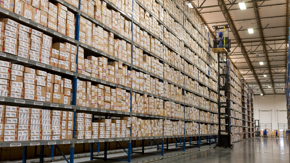 A UPSer on a forklift pulling boxes from the top level shelf of a warehouse