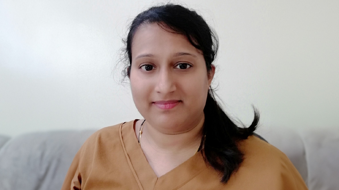 Woman smiling wearing a brown shirt.