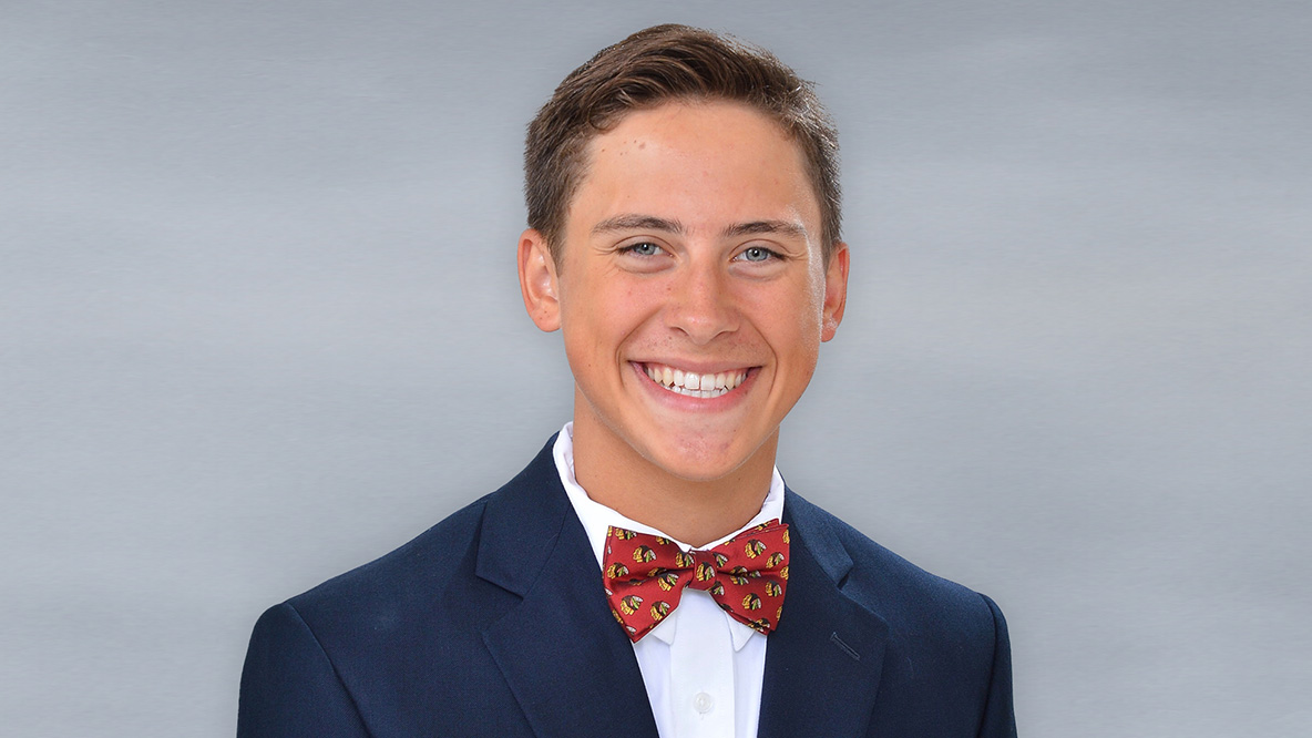 A man smiling wearing a blue suit and bowtie