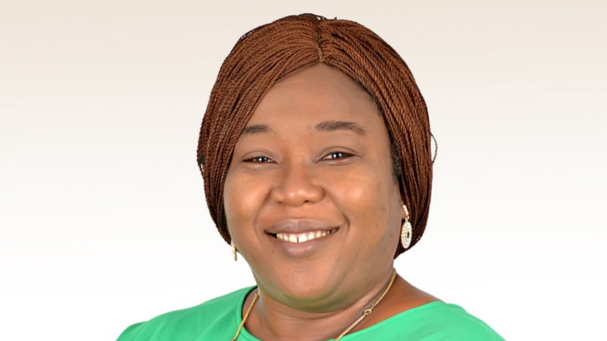 A woman smiling, wearing a green shirt and earrings