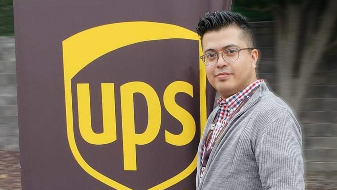 Man with glasses standing in front of a UPS banner