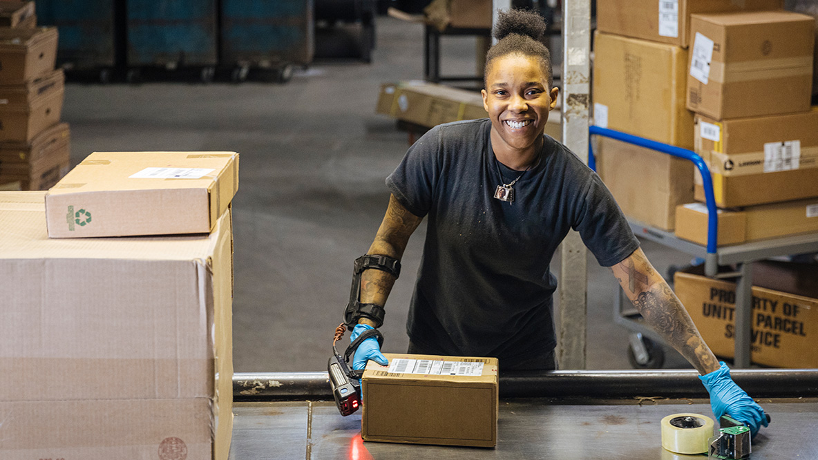 UPSer smiling and handling a package while standing in a warehouse