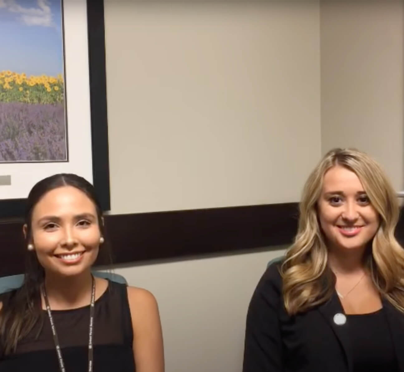 Two women in business attire are sitting and smiling