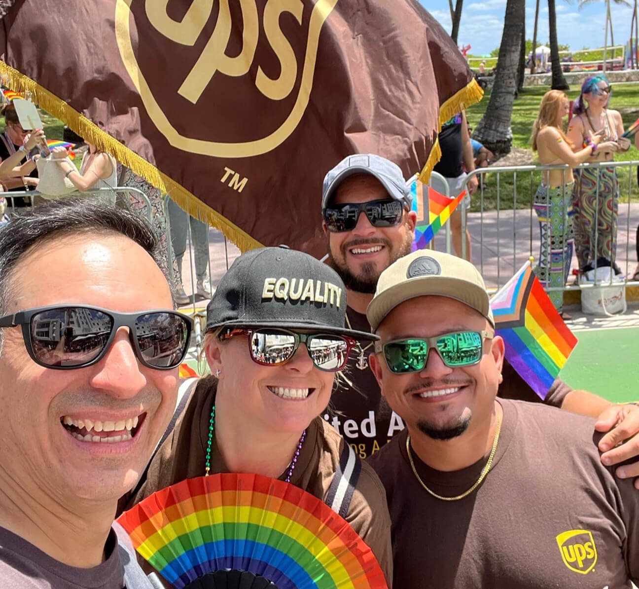 Group of people standing together and smiling in front of a UPS flag