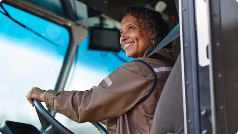 Female employee driving a UPS vehicle and smiling
