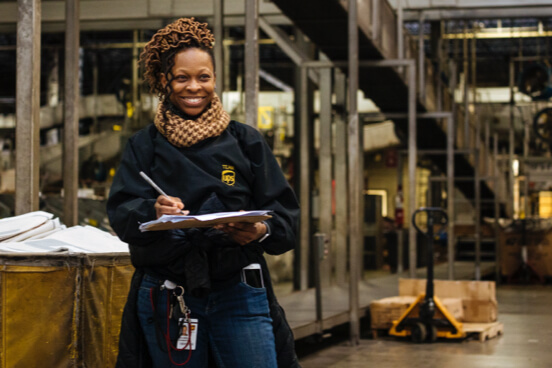 African-American female employee smiling and writing on clipboard