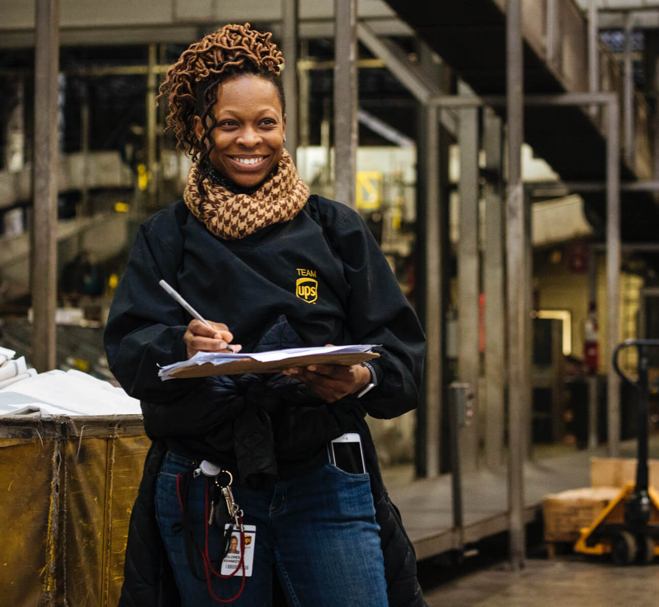 African-American female employee smiling and writing on clipboard