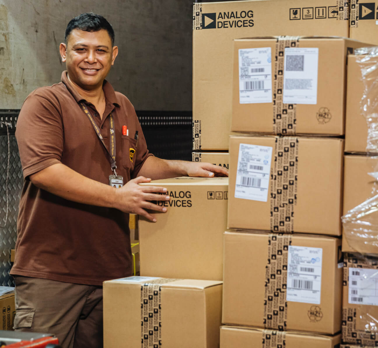 Employee smiling while standing next to a stack of boxes