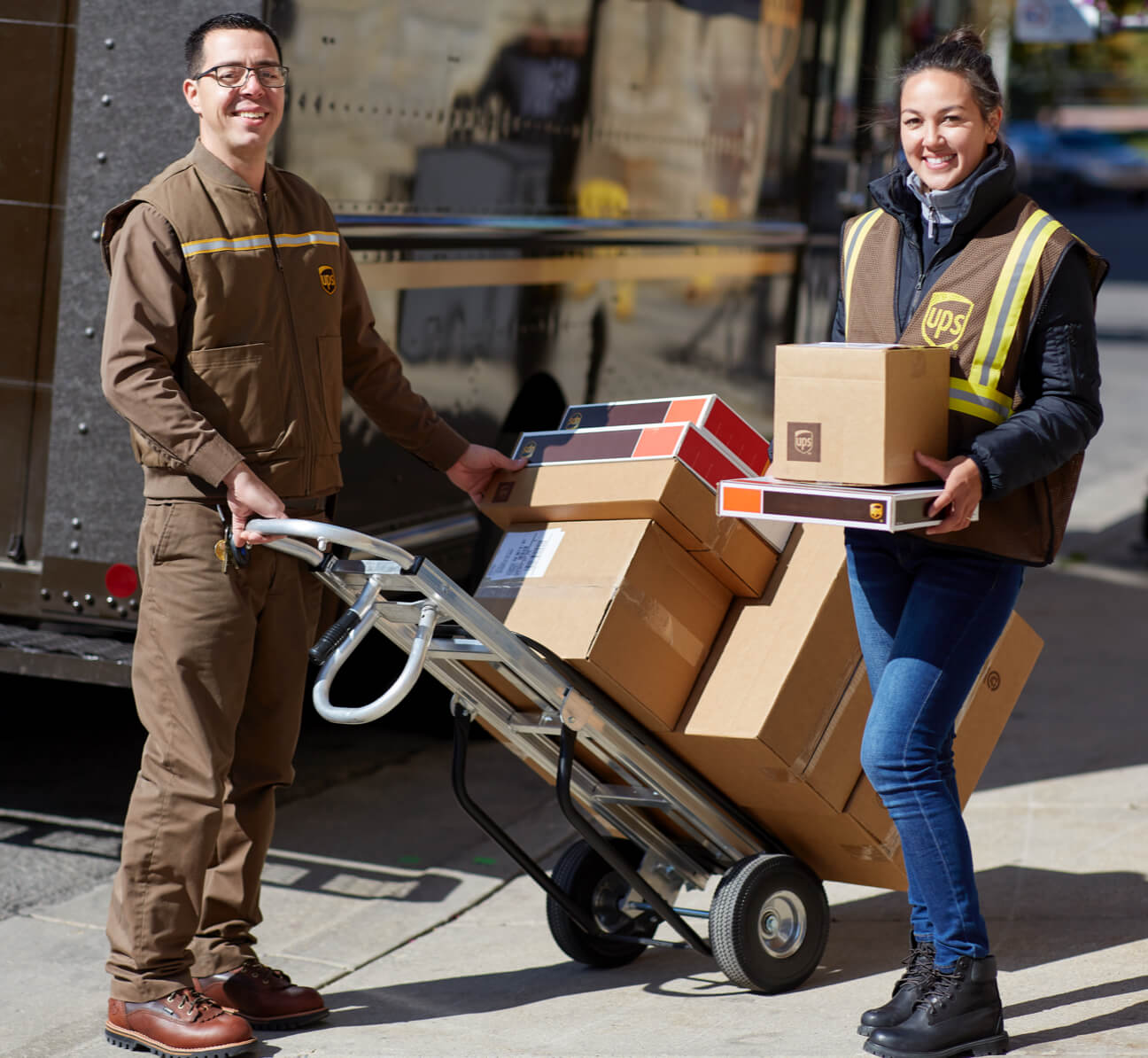 Two UPS employees loading up a dolly with packages
