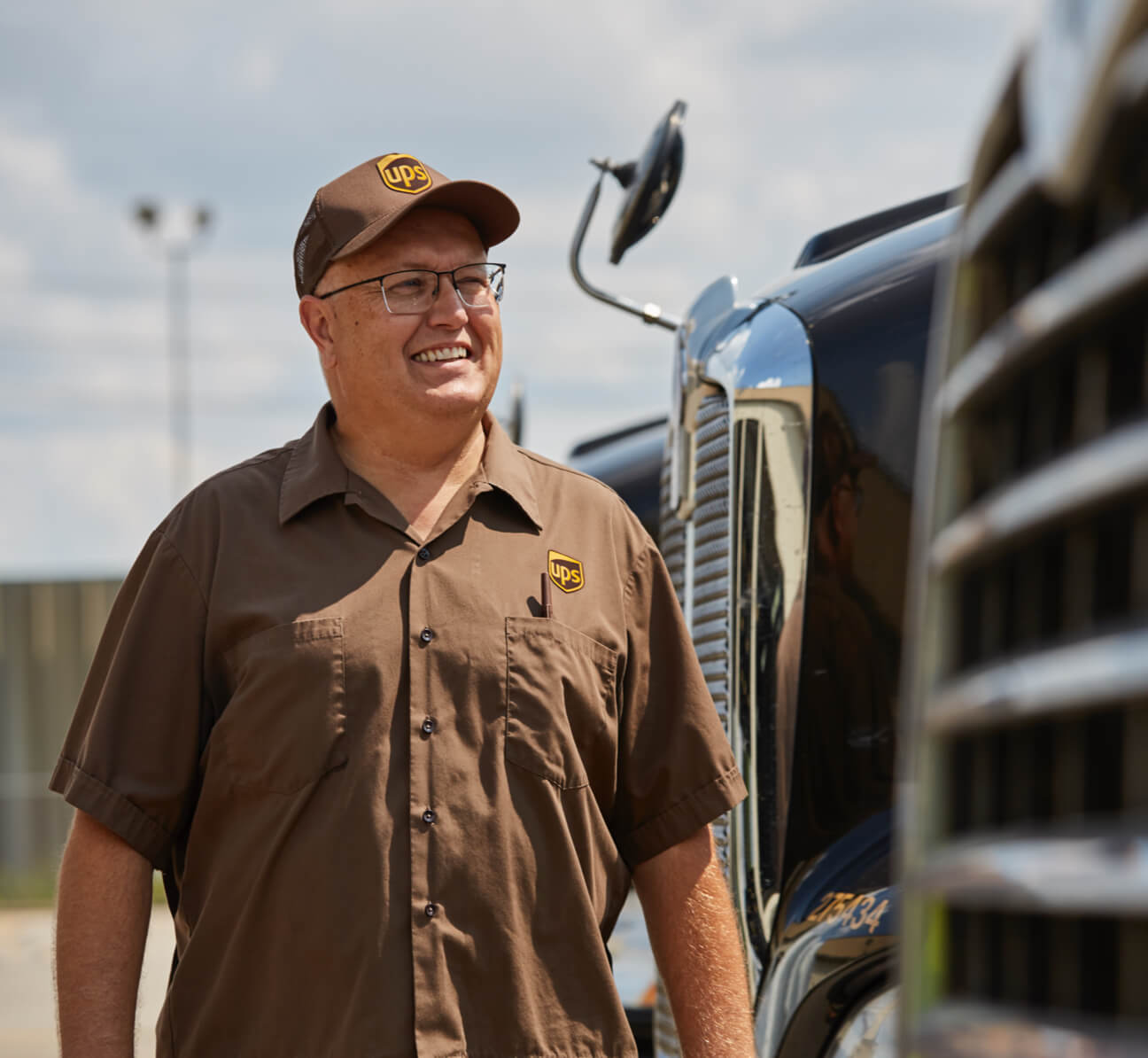 Male tractor trailer driver smiling next to semi cabs