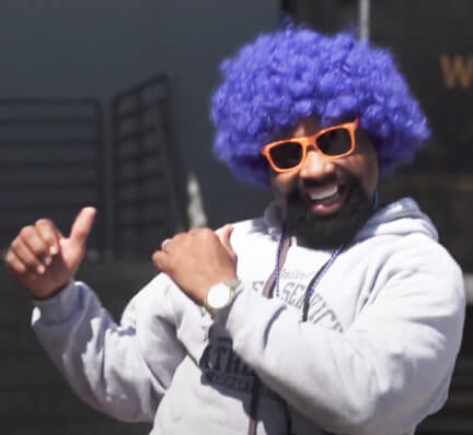 Man in funny colorful wig and sunglasses is posing in a lively way