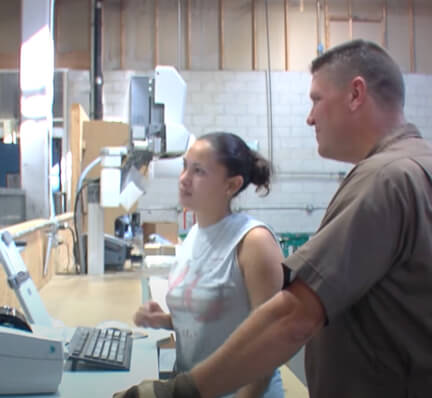 Tom standing at computer with a female employee