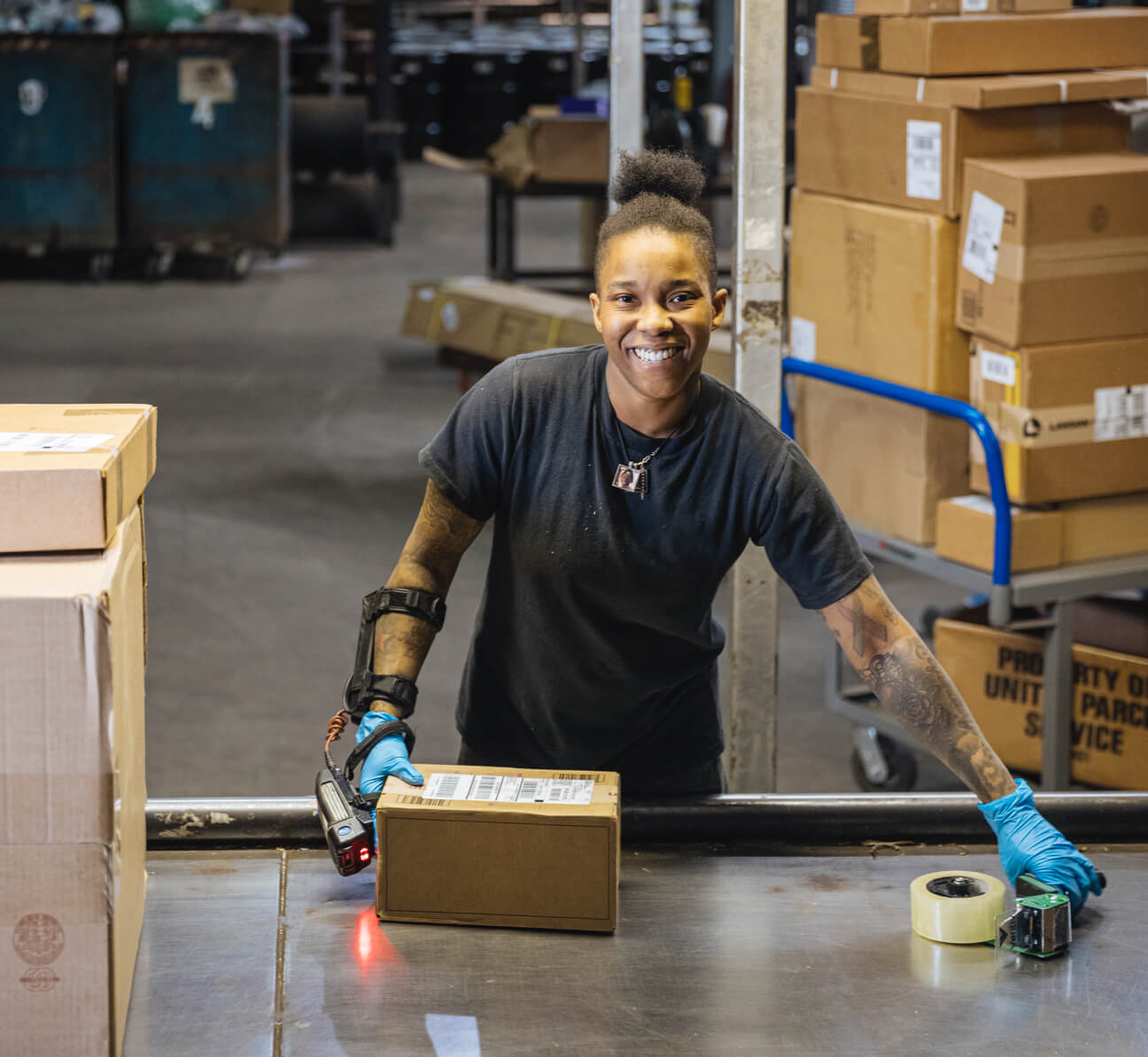 Employee smiling and handling a package while standing in a warehouse