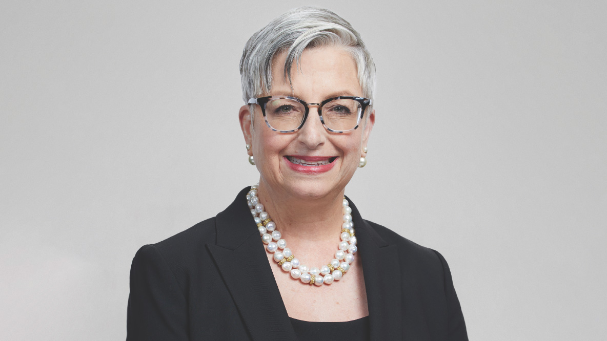 A woman (UPS CEO Carol B. Tome) wearing a pearl necklace and a black jacket