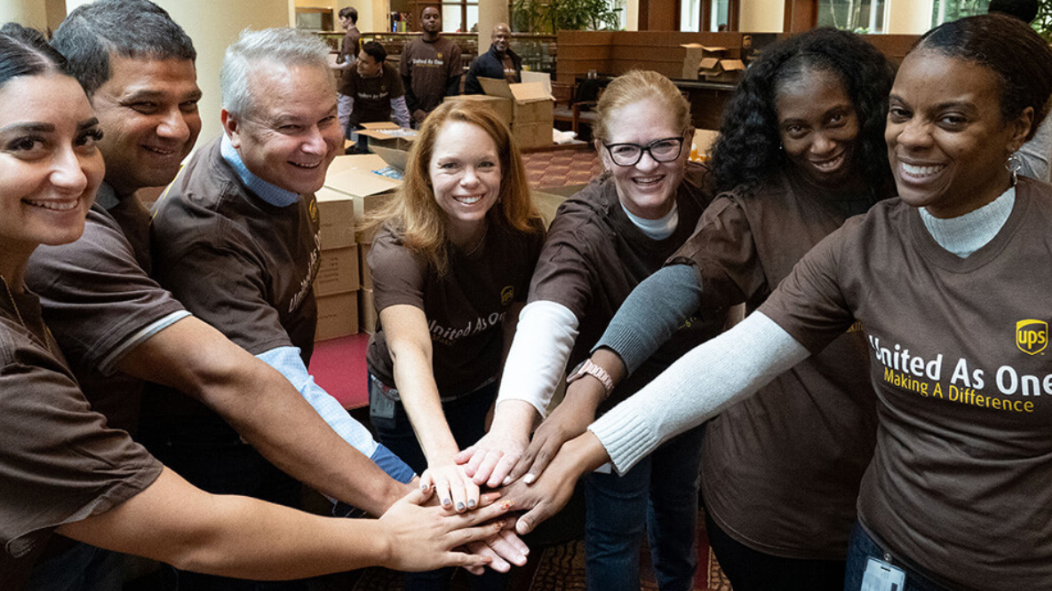 A group of UPS employees with their hands together in a circle, celebrating diversity