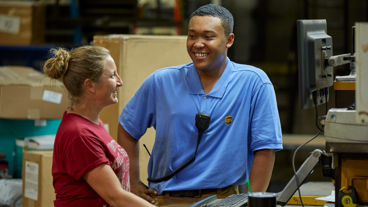 Two people standing next to each other in a warehouse, smiling